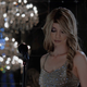 A blonde woman looks down while standing on stage in front of a microphone in the game Immortality.